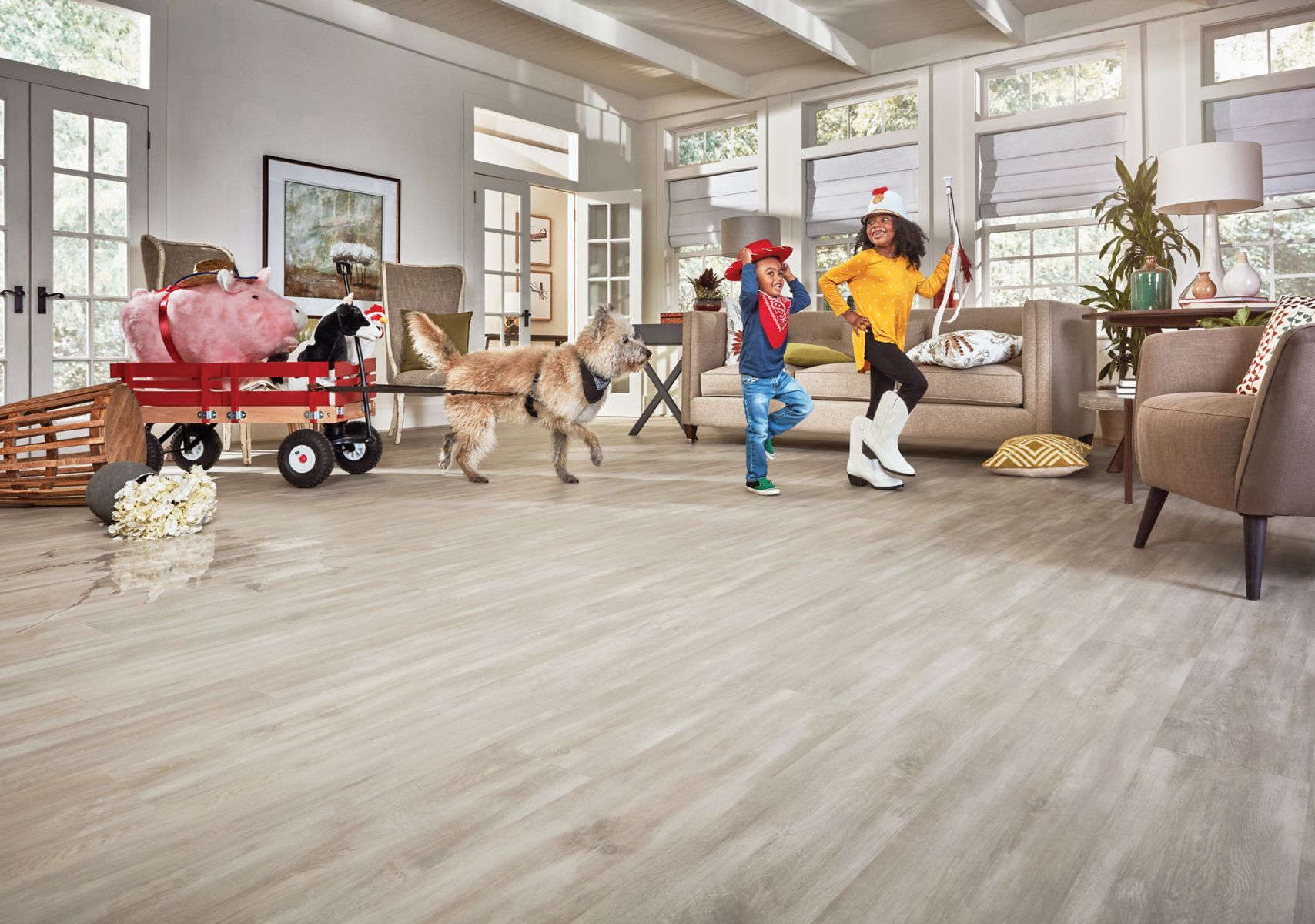 Family and dog moving across a bright Pergo interior with a spill visible on the floor