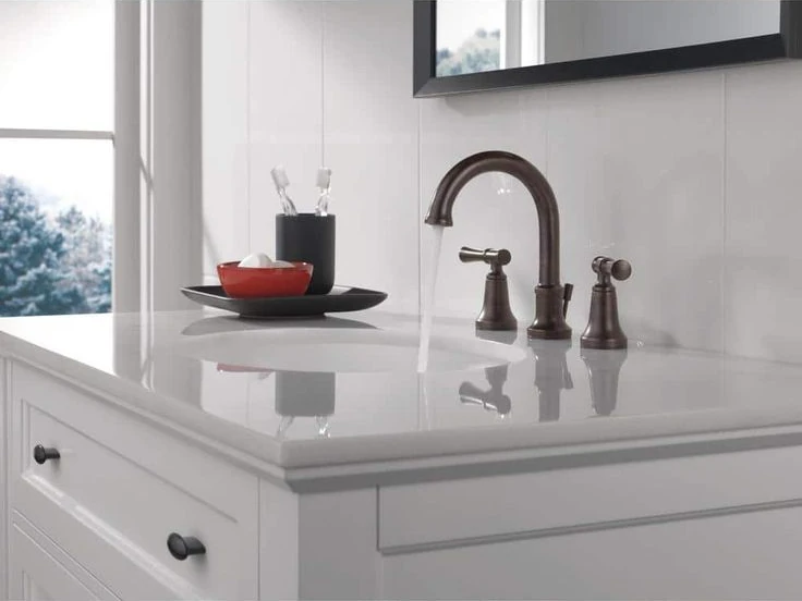 Bronze bathroom faucet installed above a white vanity basin