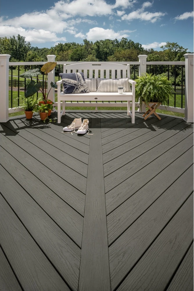 Gray composite decking with a white bench and garden beyond