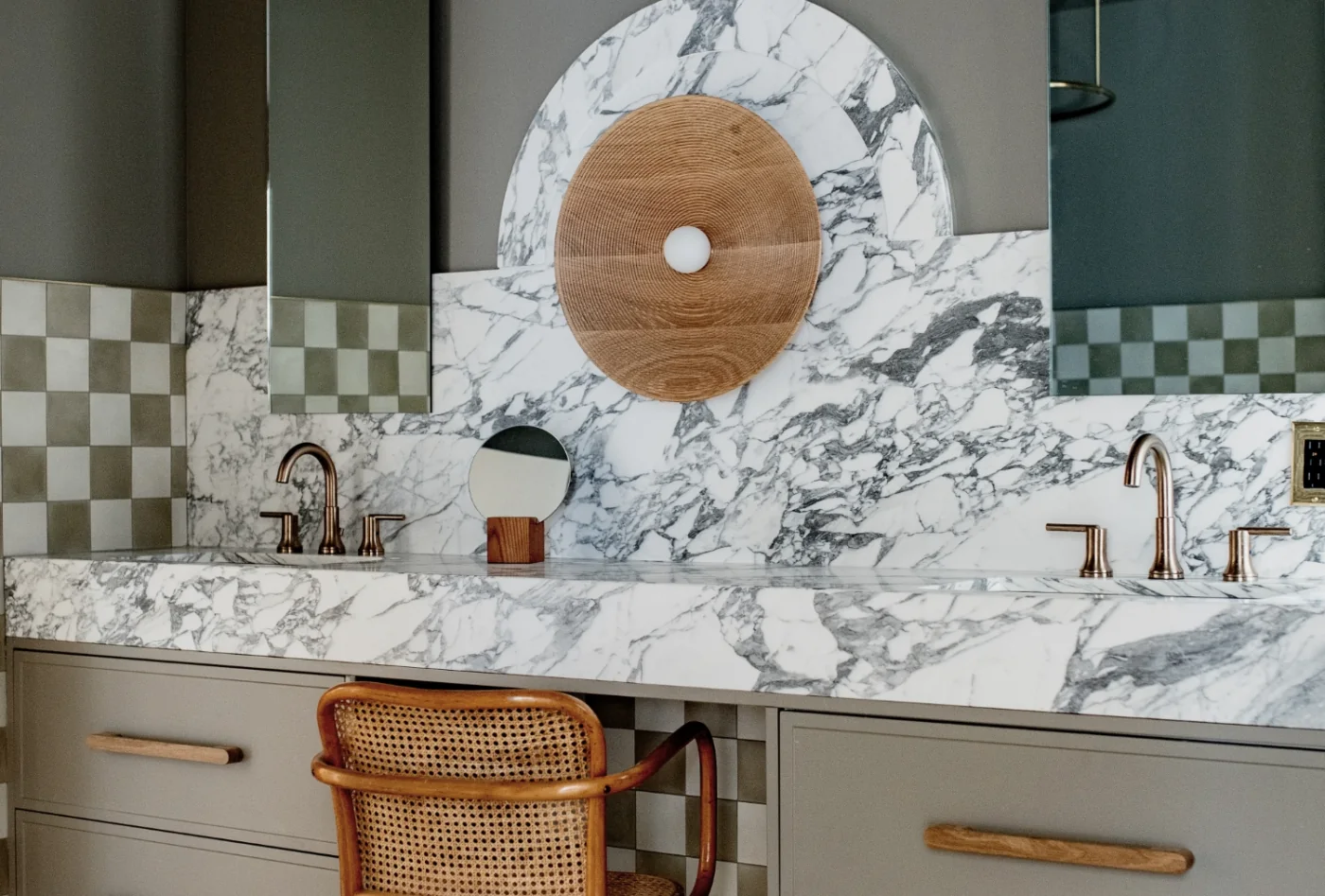 Brass Delta faucets with a sculpted marble backsplash and olive walls