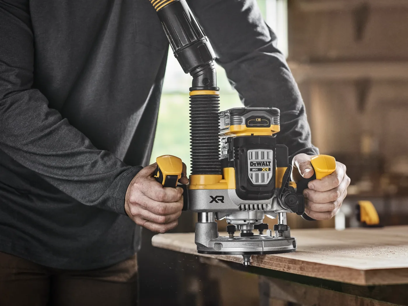 A craftsperson guides a DEWALT router across a timber board