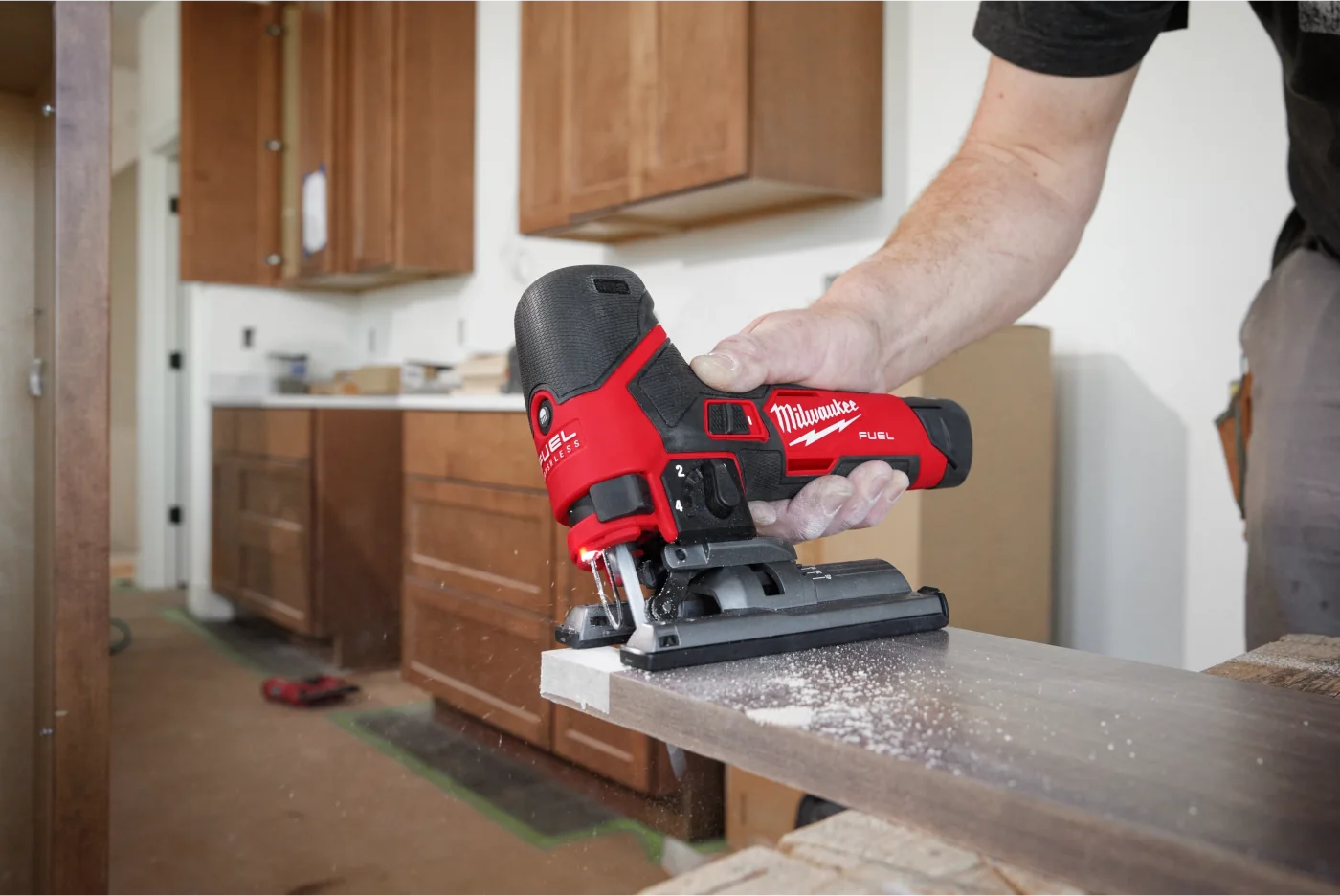A cordless jigsaw cutting a board in a kitchen under renovation