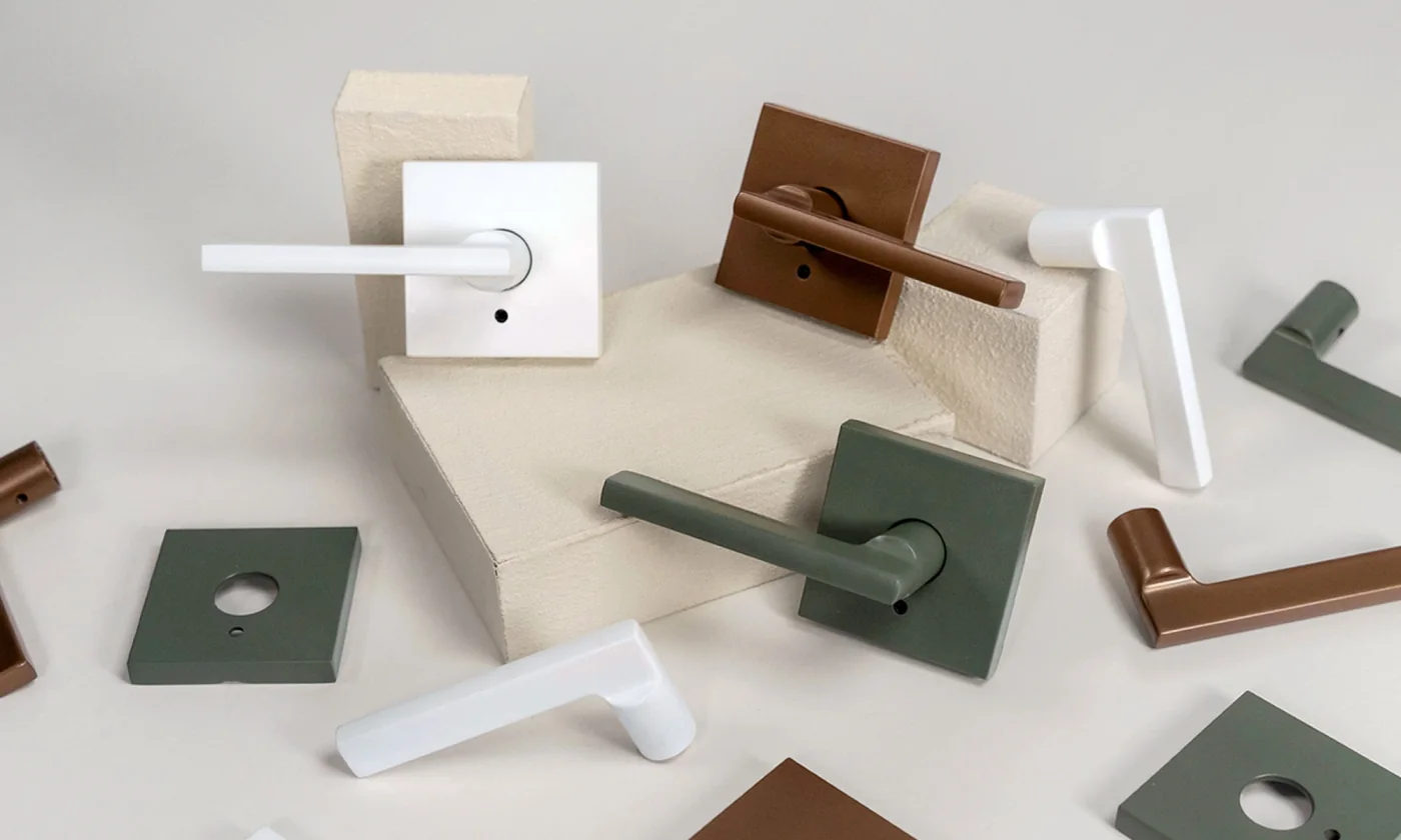 Schlage levers in white, copper and muted green arranged on a cream surface