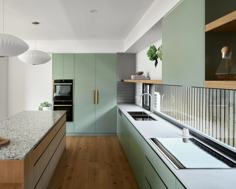 Sage green and natural oak cabinetry in a light-filled kitchen