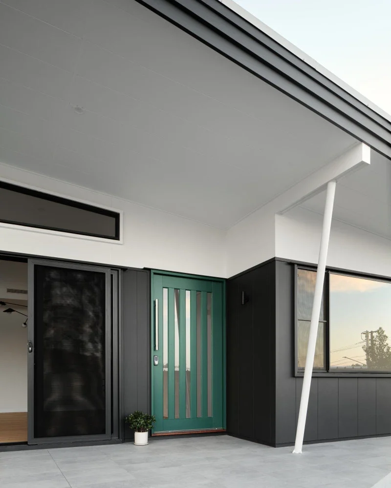 A deep green entrance door beneath a white architectural canopy