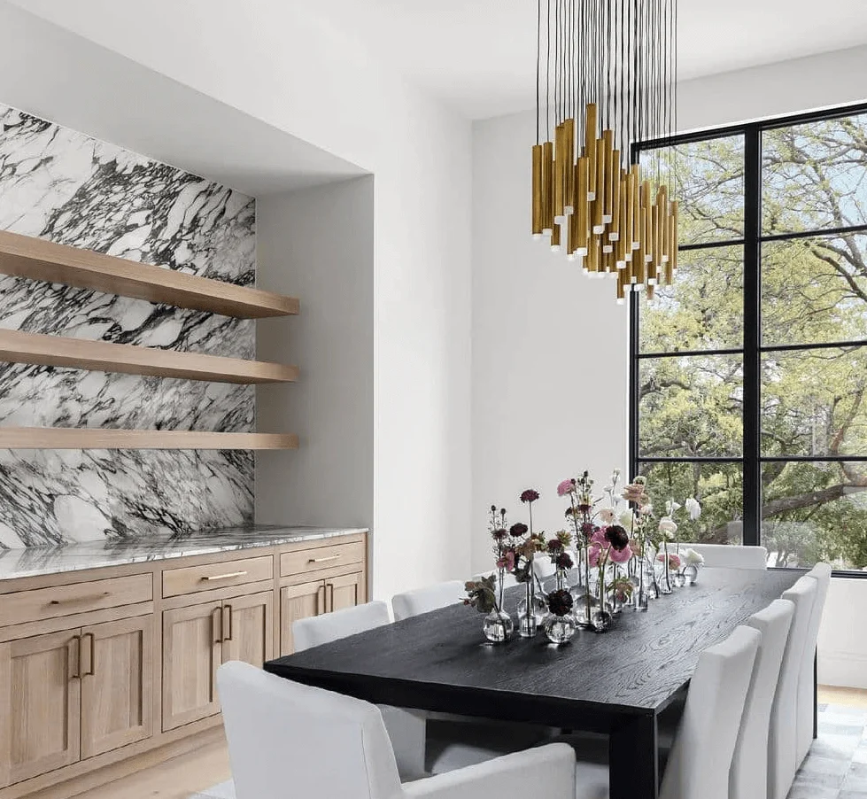 A sculptural brass pendant above a dark dining table in a bright room